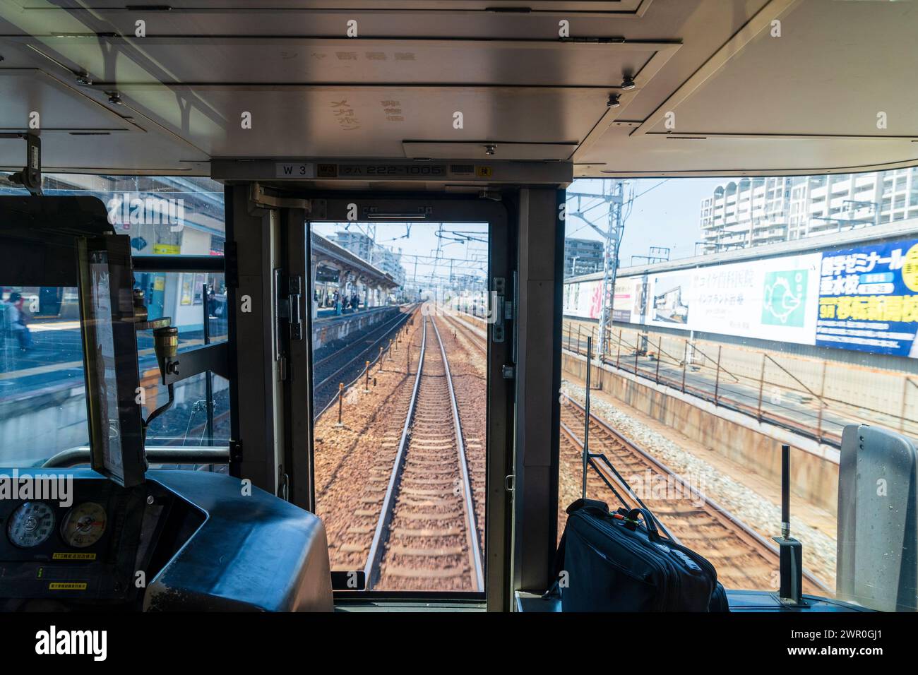 Front view through the drivers cab of a commuter train while it speeds through a town station on the JR Kobe line in Japan. Stock Photo
