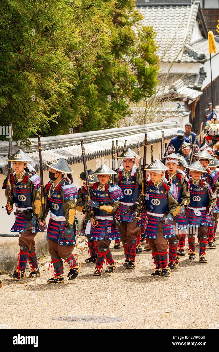 Japanese children dressed as Teppou ashigaru soldiers with matchlock guns marching along a street in the castle town of Tatsuno in the samurai parade. Stock Photo