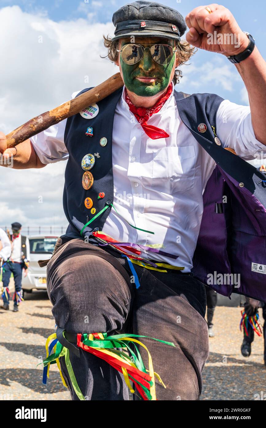 Close up of a Morrisman with green painted face from the Dead Horse Morris side dancing directly into the viewer while 'running the man down' Stock Photo