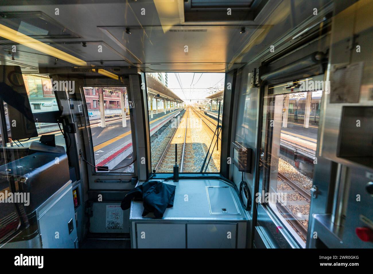 Front view through the drivers cab of a commuter train while it speeds through a town station on the JR Kobe line in Japan. Stock Photo
