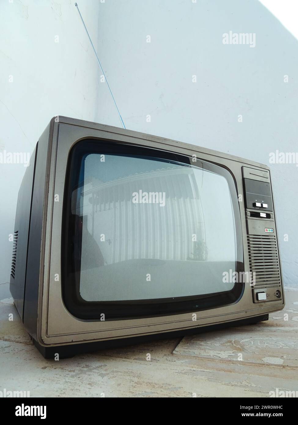 Vintage TV on concrete floor against white wall Stock Photo