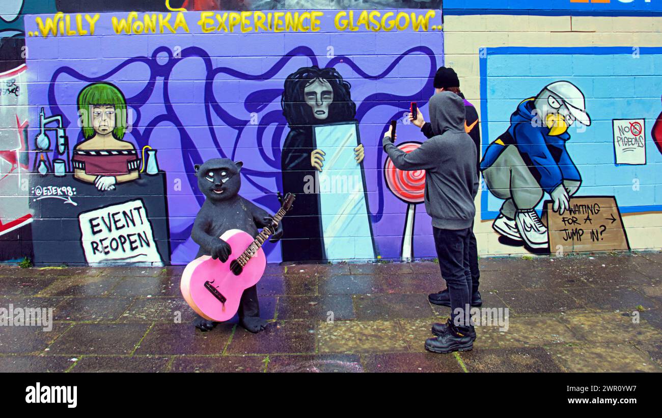 Glasgow, Scotland, UK. 10th March, 2024: Willy’s Chocolate Experience  Conceptual picture as fans  descended to the artwork on the banks  of the river clyde. Willy Wonka debacle mural appeared on the clyde side graffiti wall on the clyde walkway. The painting was created by artist Ejek after the  film experience event became national news. The artwork depicts the actresses who worked at the event as an Oompa Loompa and 'The Unknown'from the artificial intelligence script.  Credit Gerard Ferry/Alamy Live News Stock Photo