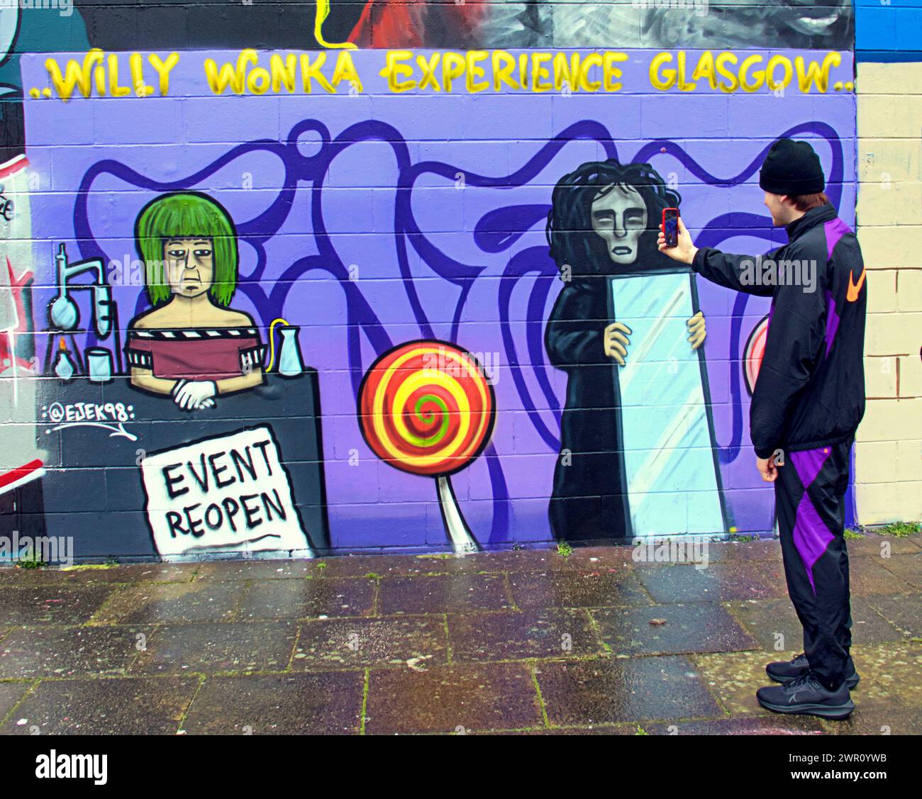 Glasgow, Scotland, UK. 10th March, 2024: Willy’s Chocolate Experience   Fan Kai and his friend descended to the artwork on the banks  of the river clyde. Willy Wonka debacle mural appeared on the clyde side graffiti wall on the clyde walkway. The painting was created by artist Ejek after the  film experience event became national news. The artwork depicts the actresses who worked at the event as an Oompa Loompa and 'The Unknown'from the artificial intelligence script.  Credit Gerard Ferry/Alamy Live News Stock Photo
