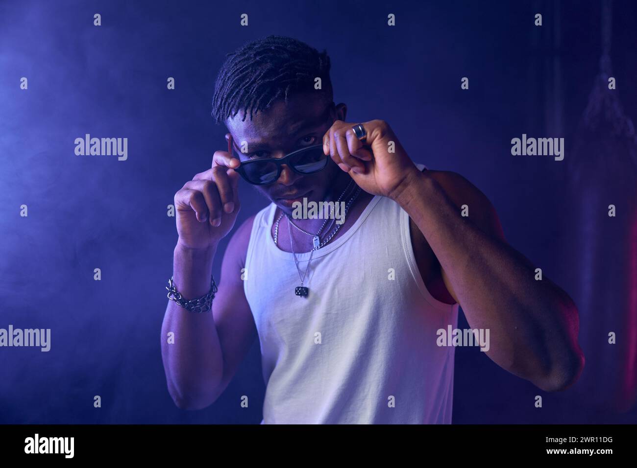 Young guy rapper posing for camera in neon light Stock Photo - Alamy