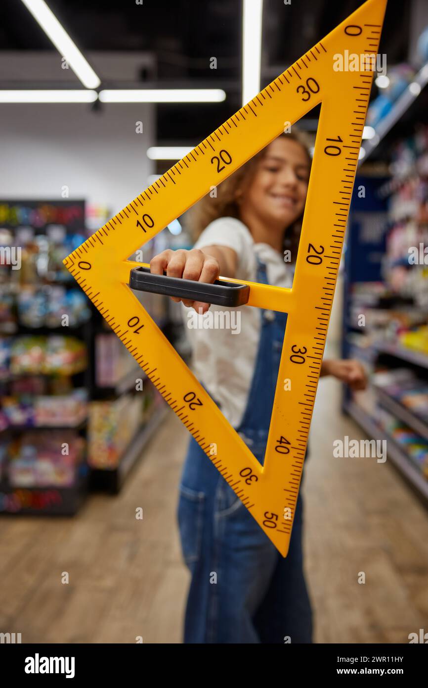 School girl student holding huge triangle ruler stationery in hands ...