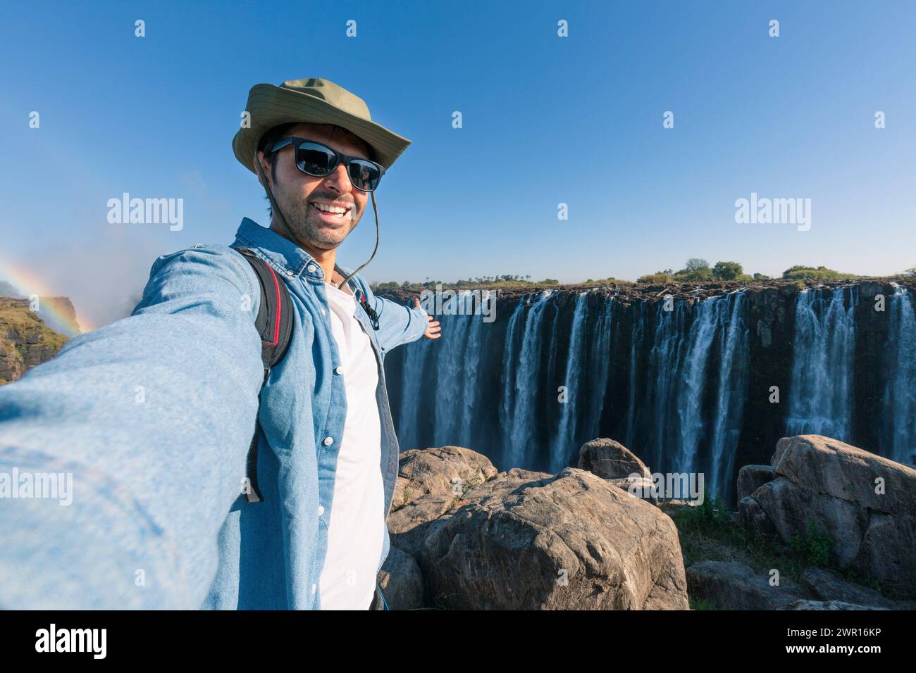A tourist takes a selfie at Victoria Falls on the Zambezi River, located on the border between Zambia and Zimbabwe, the largest waterfall in the world Stock Photo
