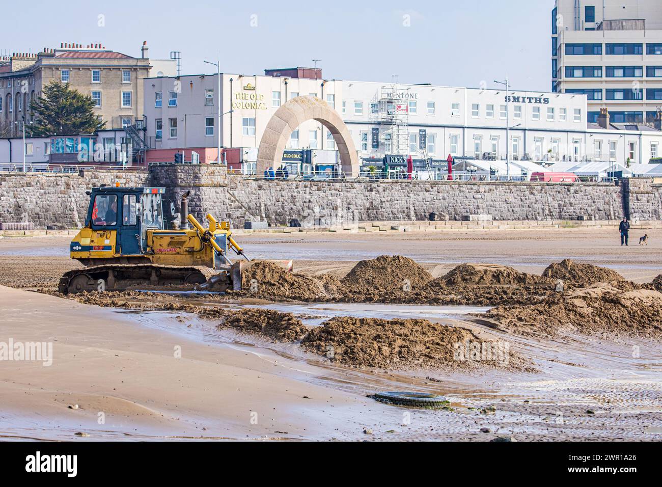 Bulldozer moving sand on Weston Super Mare Beach to combat the effect of long shore drift before the summer season Stock Photo
