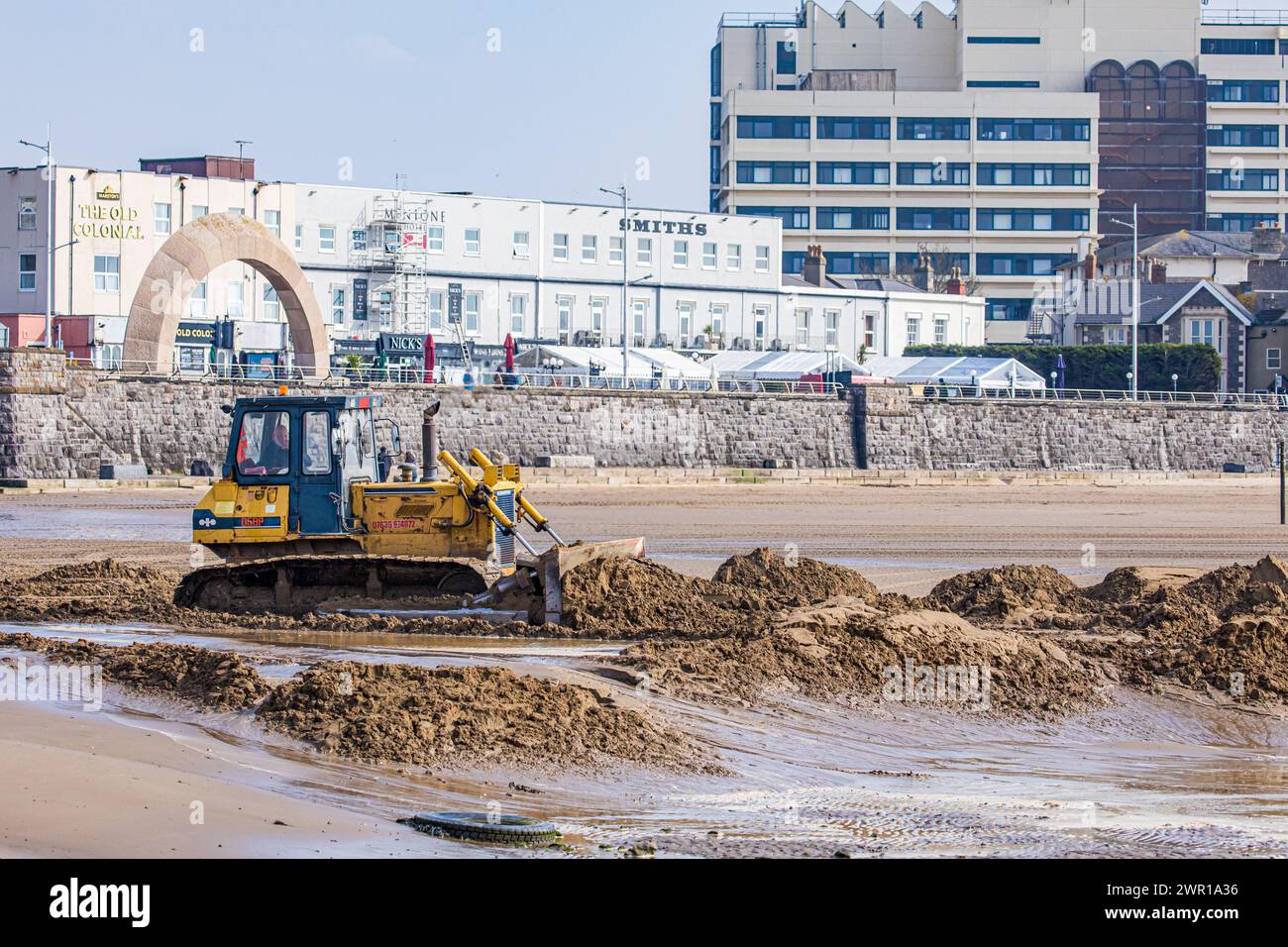 Bulldozer moving sand on Weston Super Mare Beach to combat the effect of long shore drift before the summer season Stock Photo