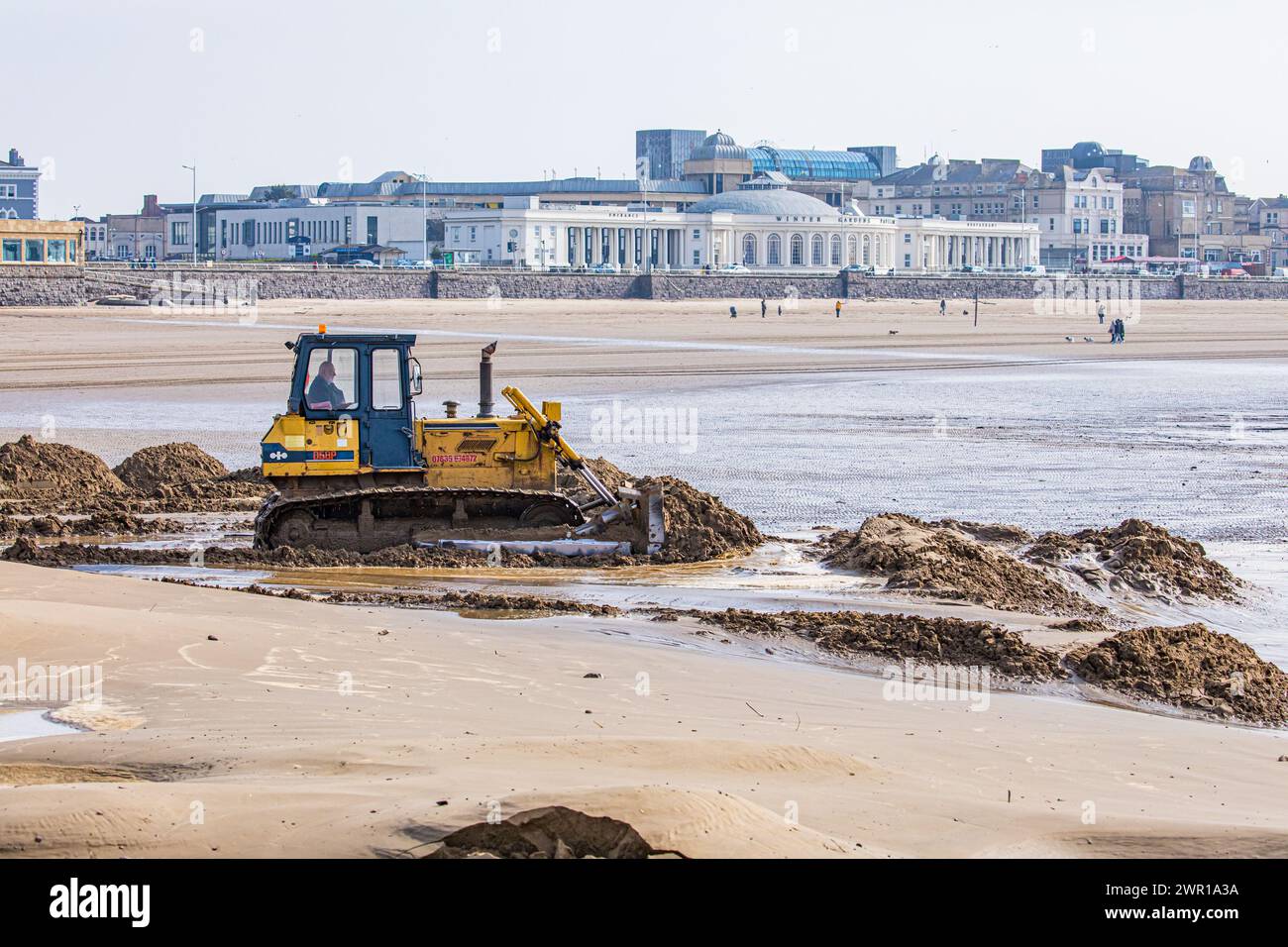 Bulldozer moving sand on Weston Super Mare Beach to combat the effect of long shore drift before the summer season Stock Photo
