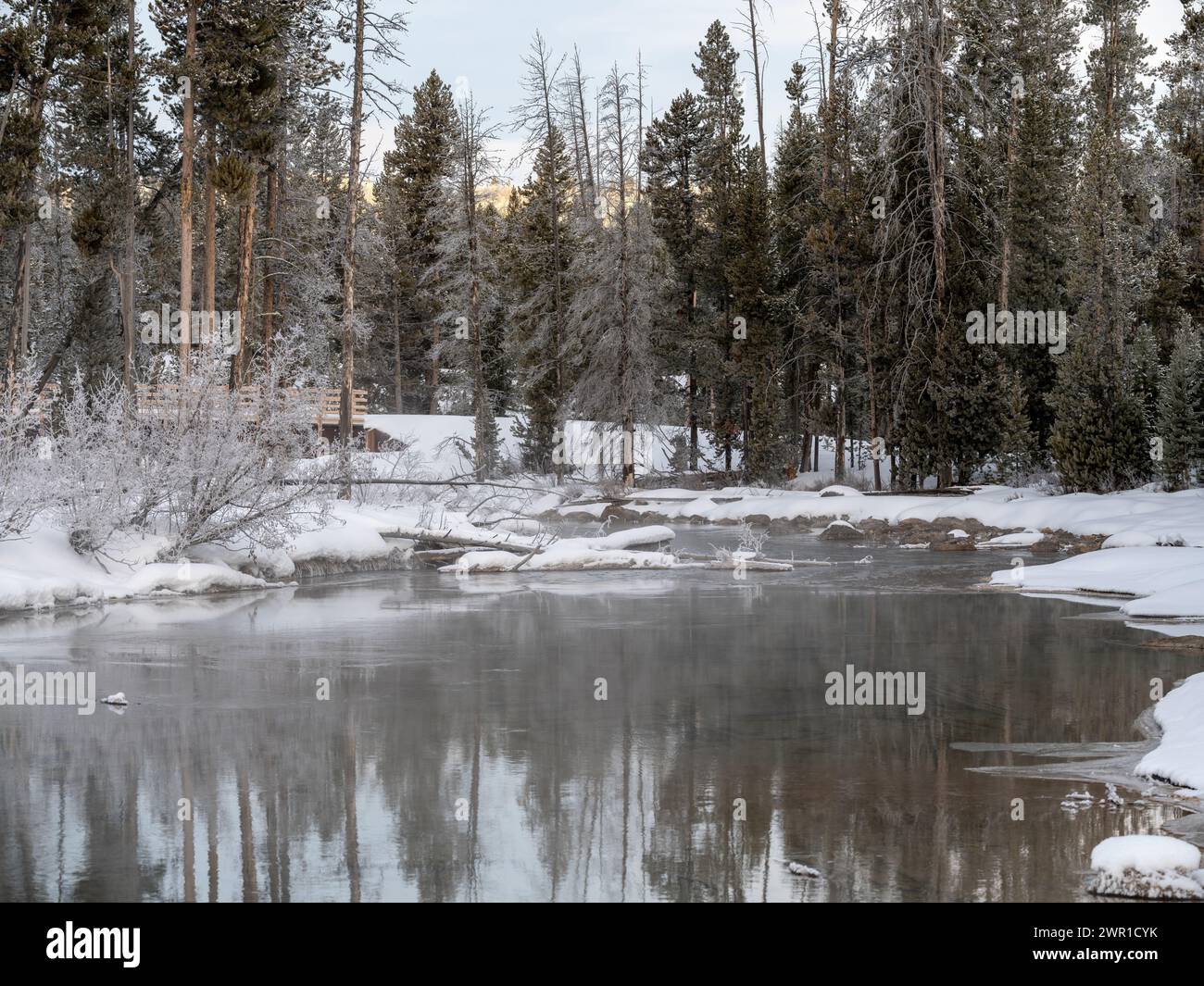 Snow banked creek in Idaho with distant bridge Stock Photo