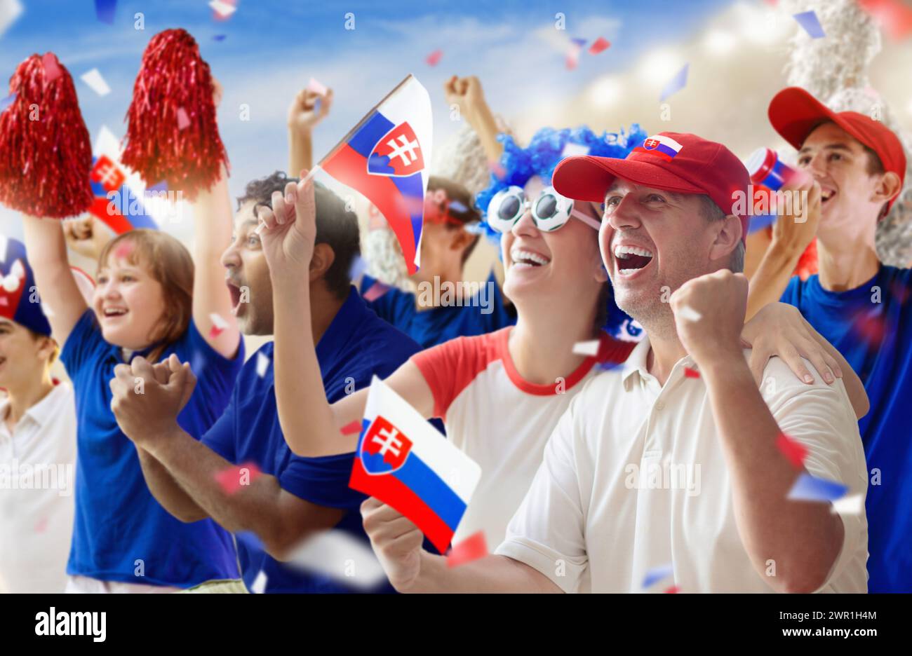 Slovakia football supporter on stadium. Slovak fans on soccer pitch watching team play. Group of supporters with flag and national jersey cheering Stock Photo