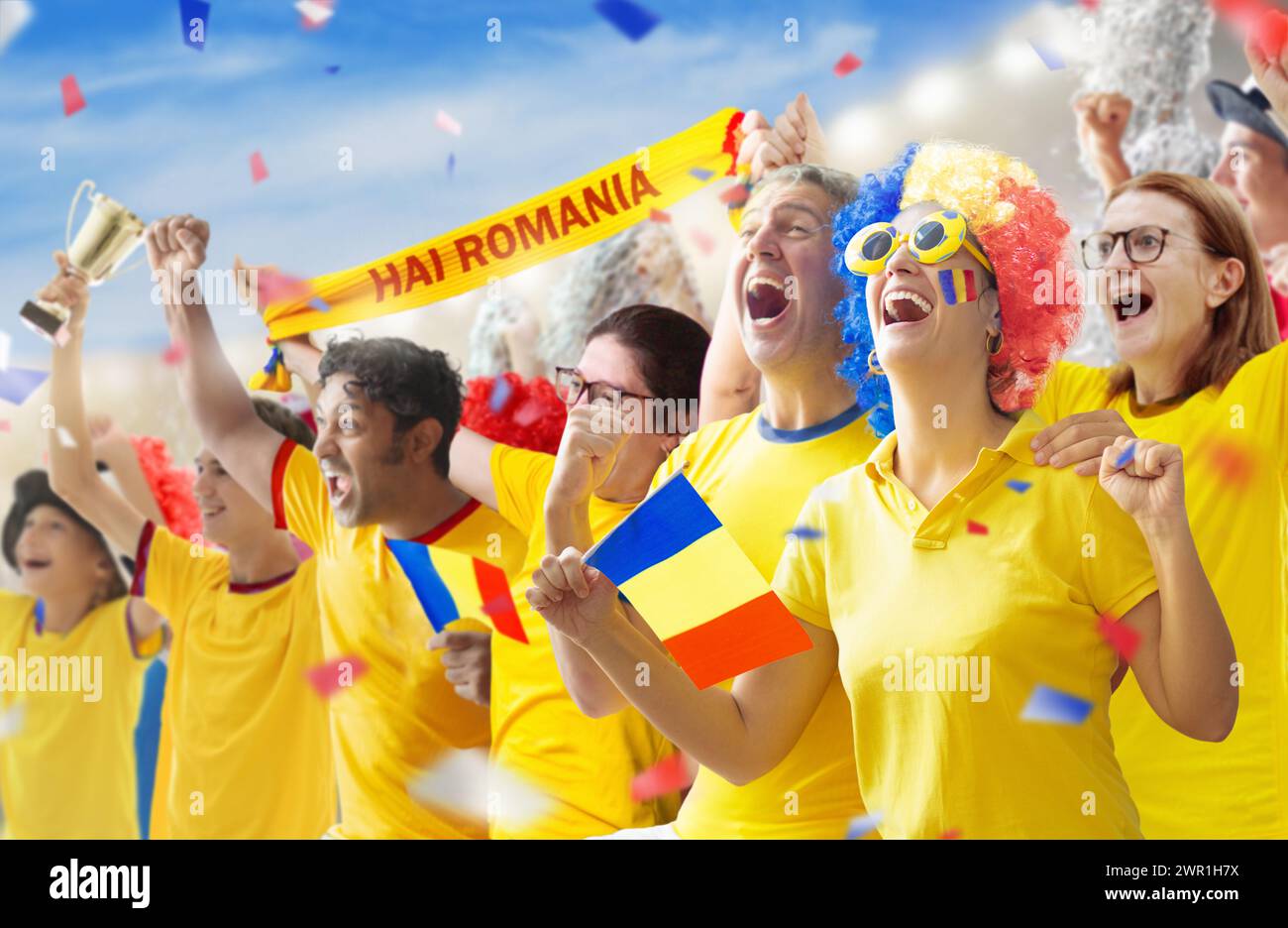 Romania football supporter on stadium. Romanian fans on soccer pitch watching team play. Group of supporters with flag and national jersey cheering Stock Photo