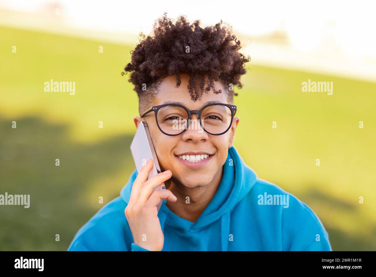 Portrait of smiling black student guy talking on cellphone outdoors Stock Photo