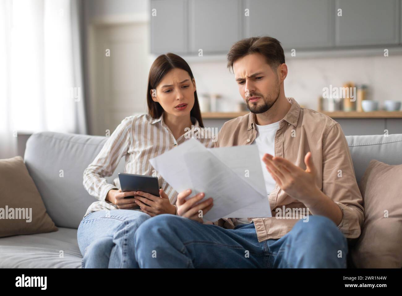Confused spouses reviewing documents with tablet Stock Photo