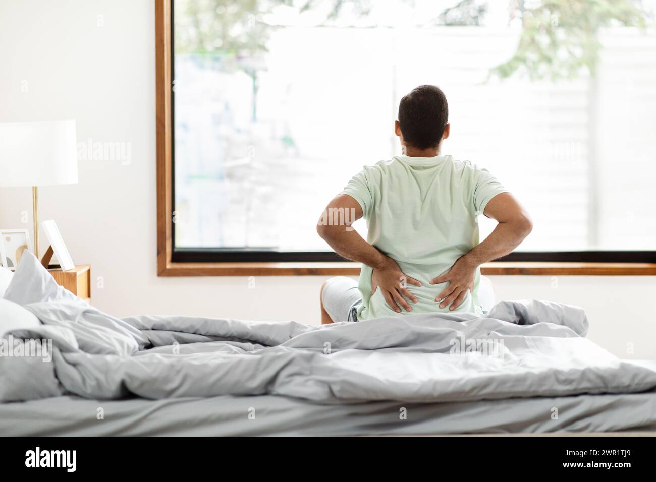 tired-black-man-suffering-from-back-pain-after-waking-up-stock-photo