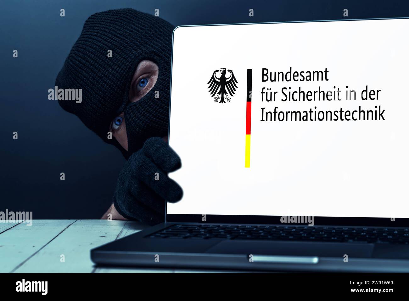 10 March 2024: Masked person, symbolizing a criminal, next to a laptop ...