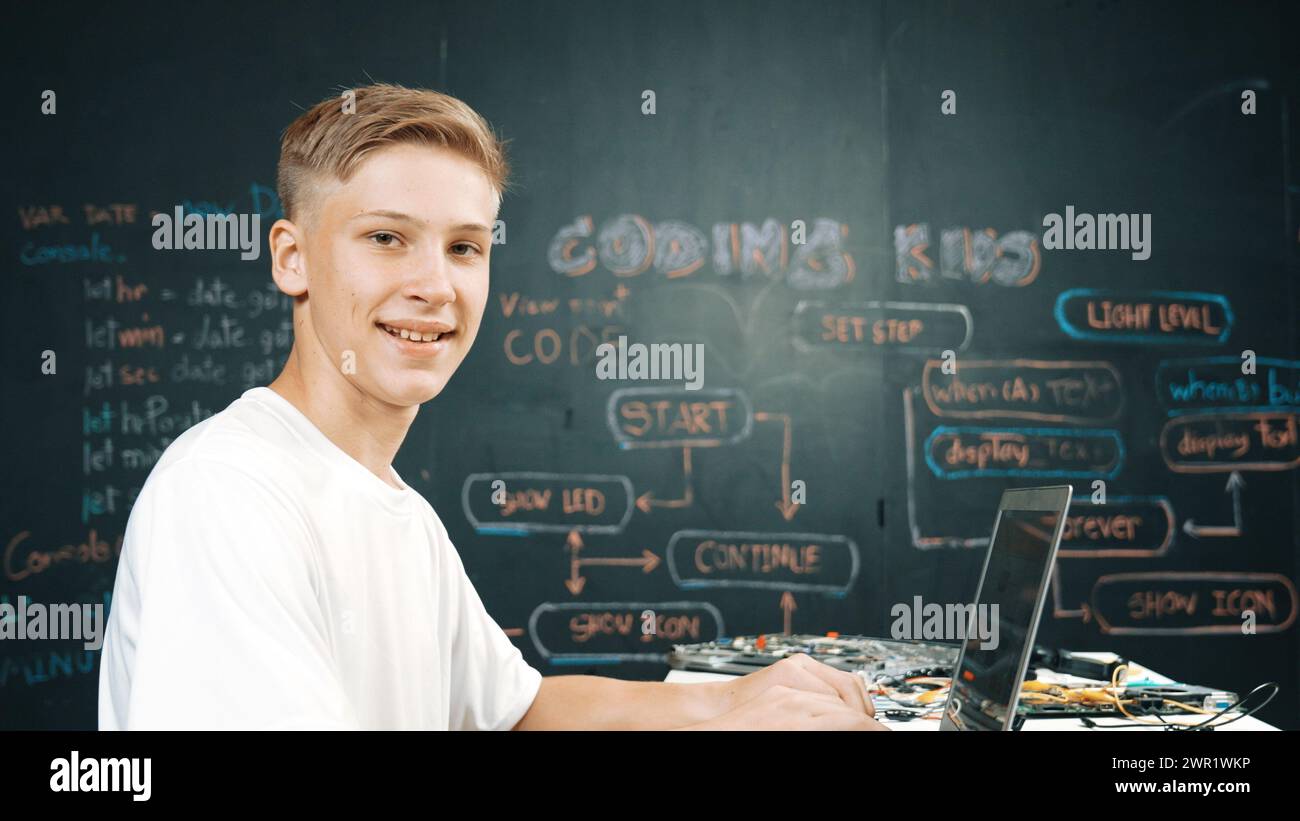 Caucasian boy coding and programing system while looking at laptop ...