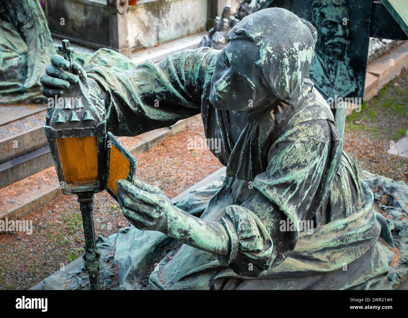 The tomb of Carlo Besana and Vittoria Carcano of a women lighting a lamp, Monumental Cemetery, Milan, Lombardy, Italy. Stock Photo