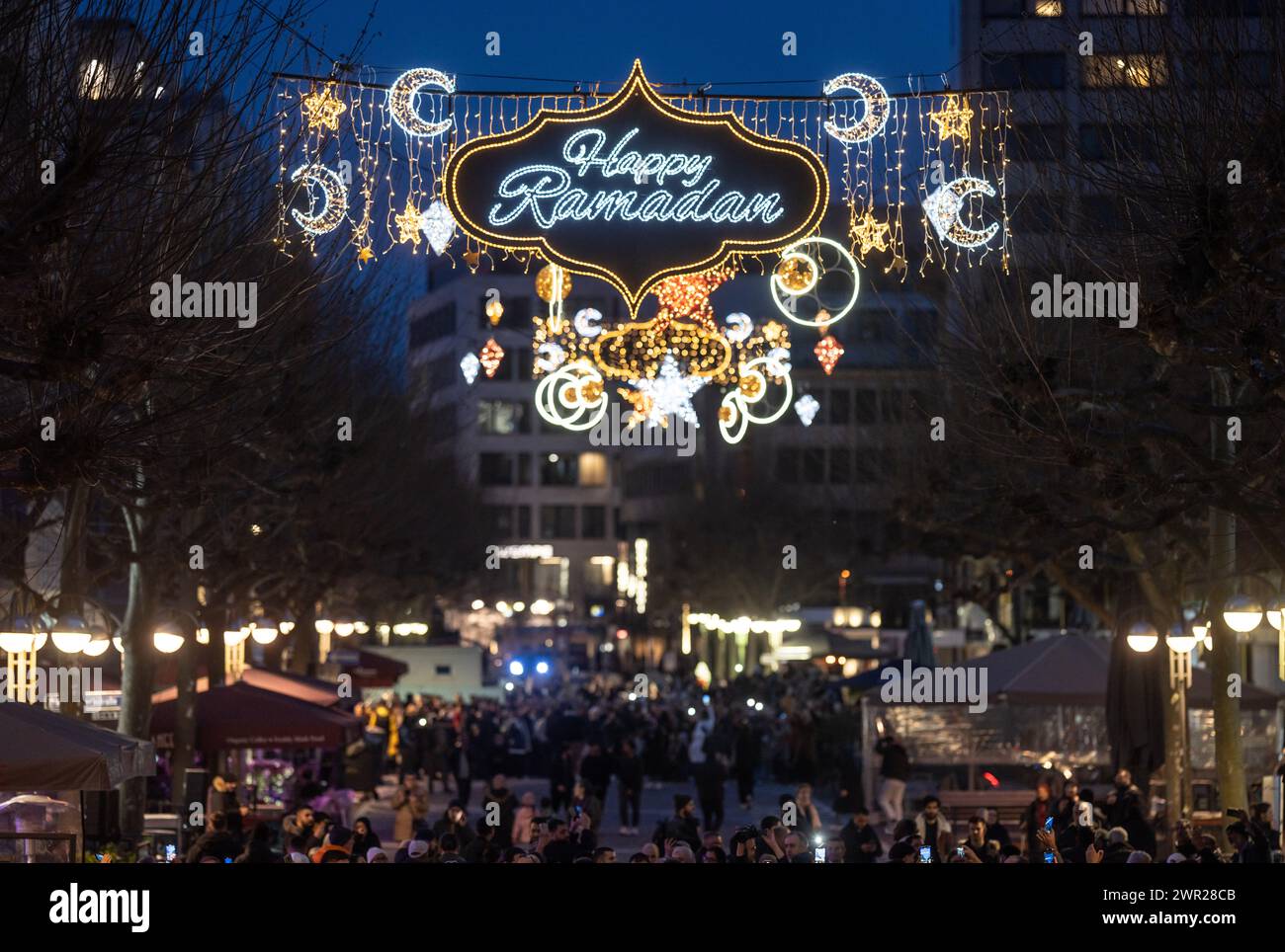 10 March 2024, Hesse, Frankfurt/Main: Stars, moons and the words 'Happy Ramadan' light up Frankfurt's Fressgass at nightfall. The illumination is considered unique in Germany and is aimed at Muslims who are currently observing the fasting month of Ramadan. Photo: Frank Rumpenhorst/dpa Stock Photo