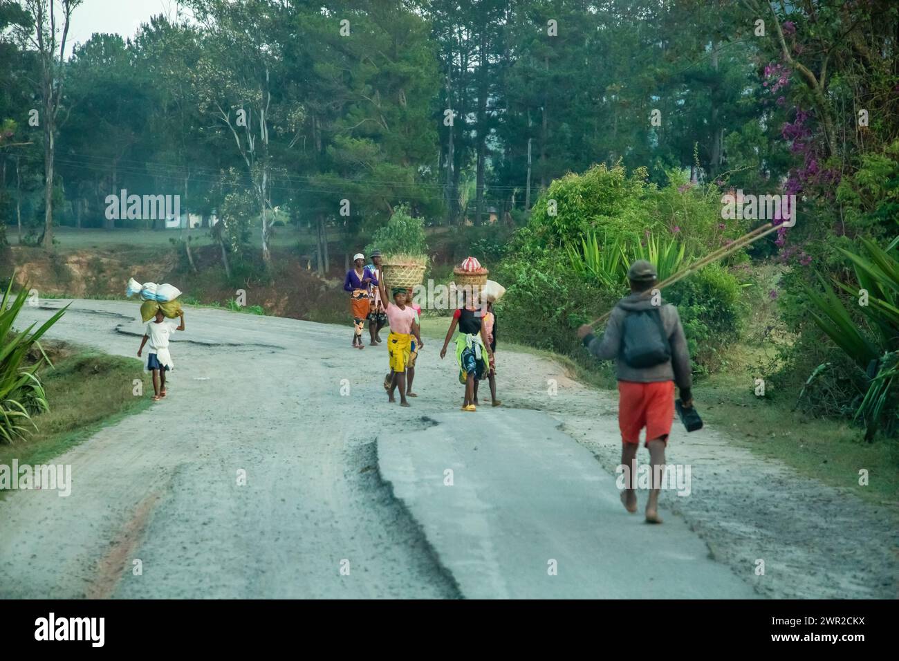 Madagascar, 19 october 2023. Roads of Madagascar. various Malagasy people walk along a dusty road in the early morning Stock Photo