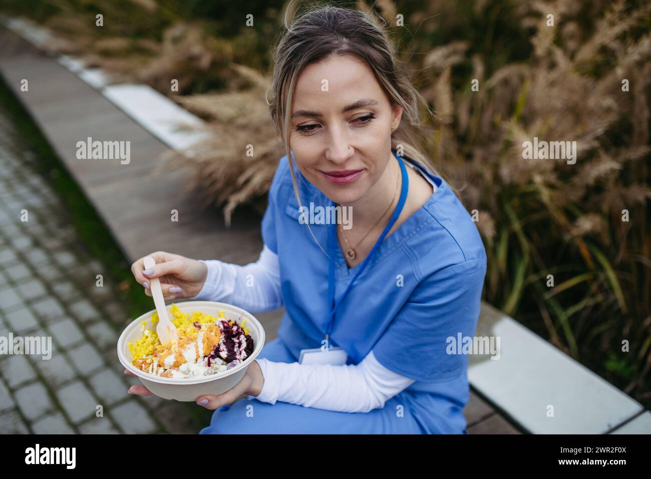 Nurse having healthy lunch in front of hospital building, taking break