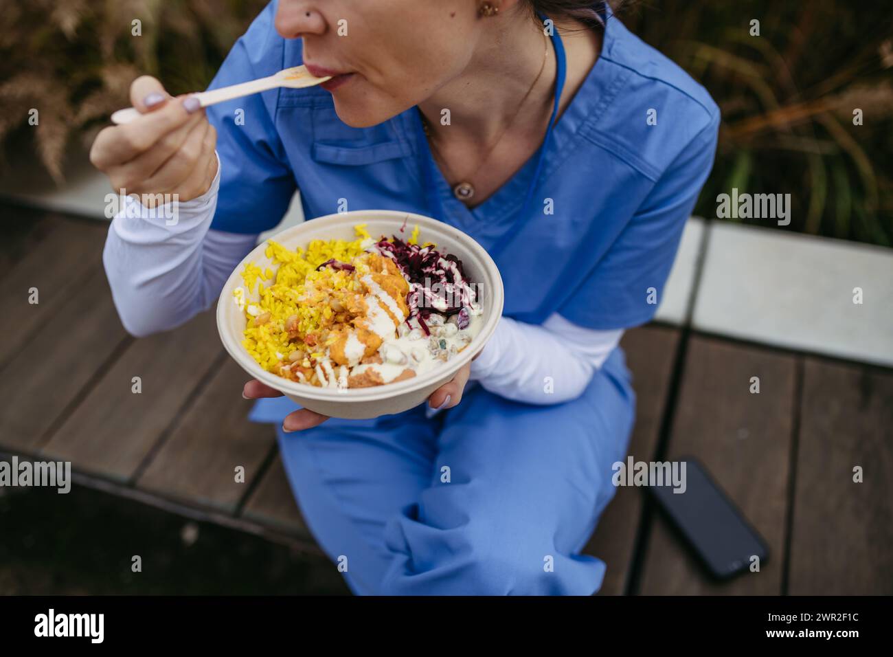 Nurse having healthy lunch in front of hospital building, taking break