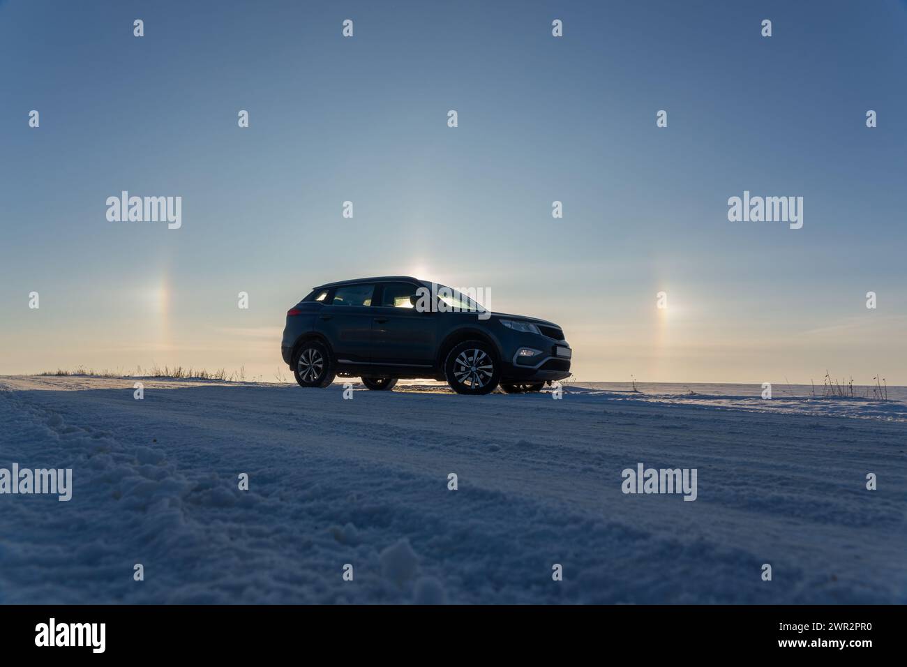 Winter landscape with car and circular halo phenomena around the sun in ...