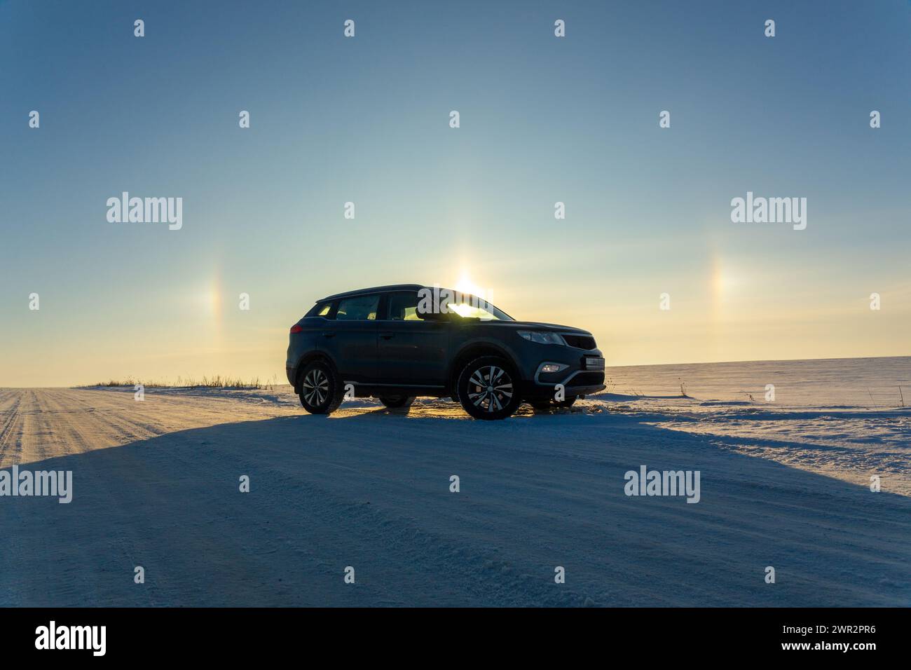 Winter landscape with car and circular halo phenomena around the sun in ...