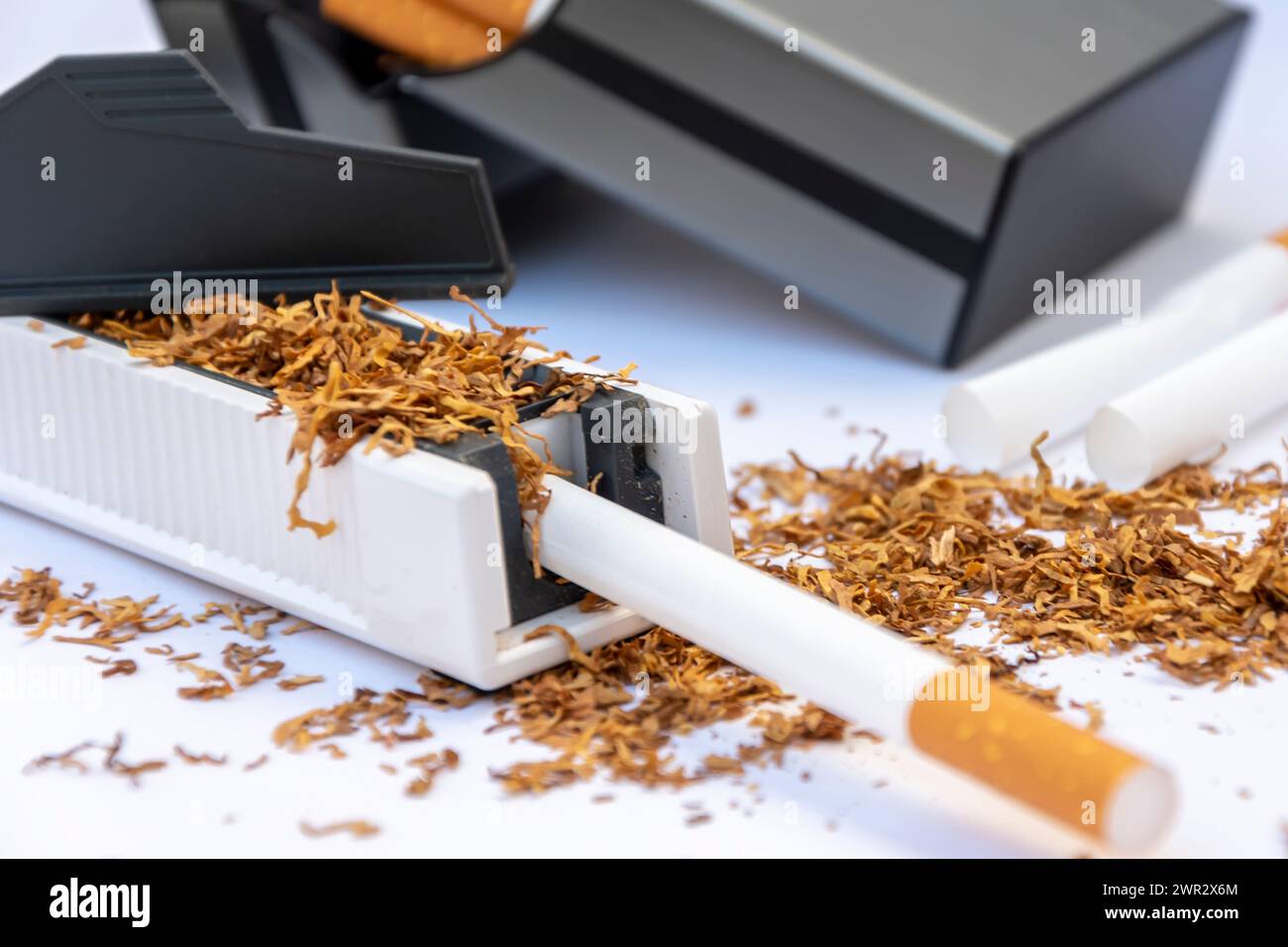 Manual machine for stuffing cigarette casings with tobacco, scattered empty cigarettes and a pile of tobacco on a white background, cigarette case wit Stock Photo