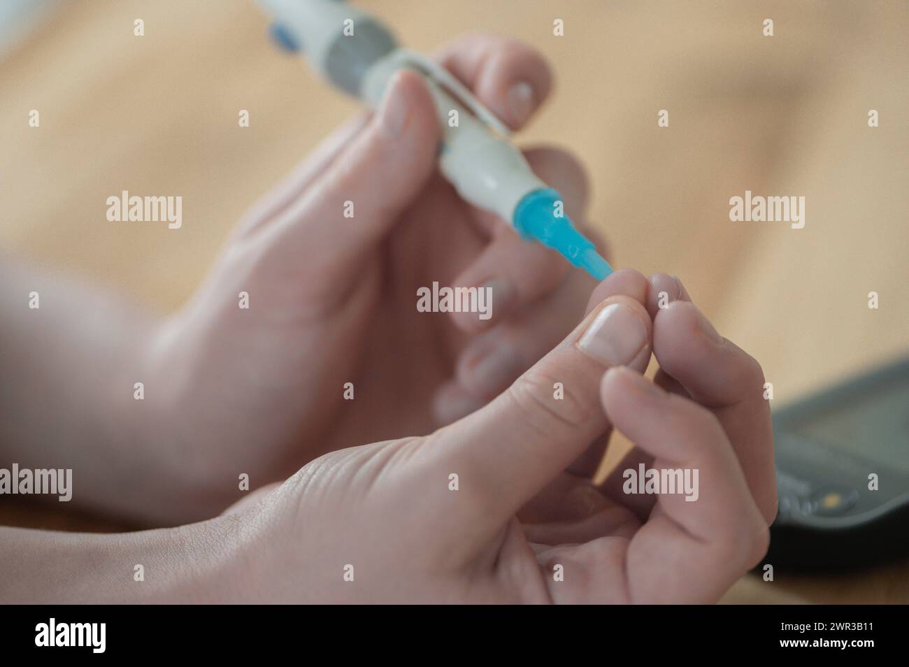 On the left a child's hand holding a lancet, lancing device, and pricking itself to determine