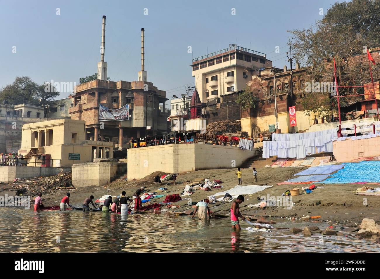 Community washing of clothes on the riverbank with a view of buildings and cultural life, Varanasi, Uttar Pradesh, India Stock Photo