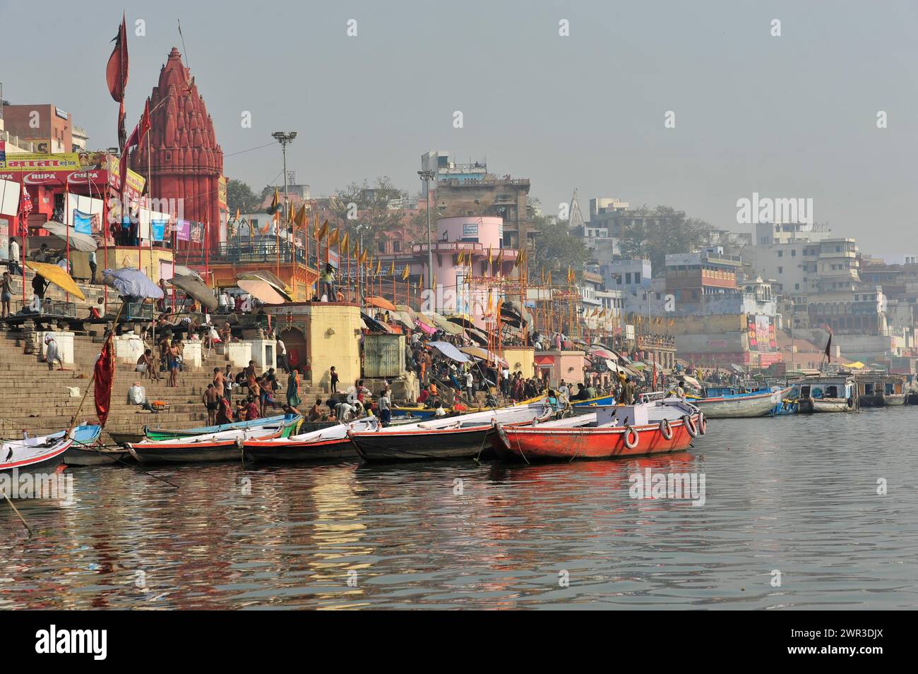 View of boat-filled ghats and a riverside temple, sign of religious activity, Varanasi, Uttar Pradesh, India Stock Photo