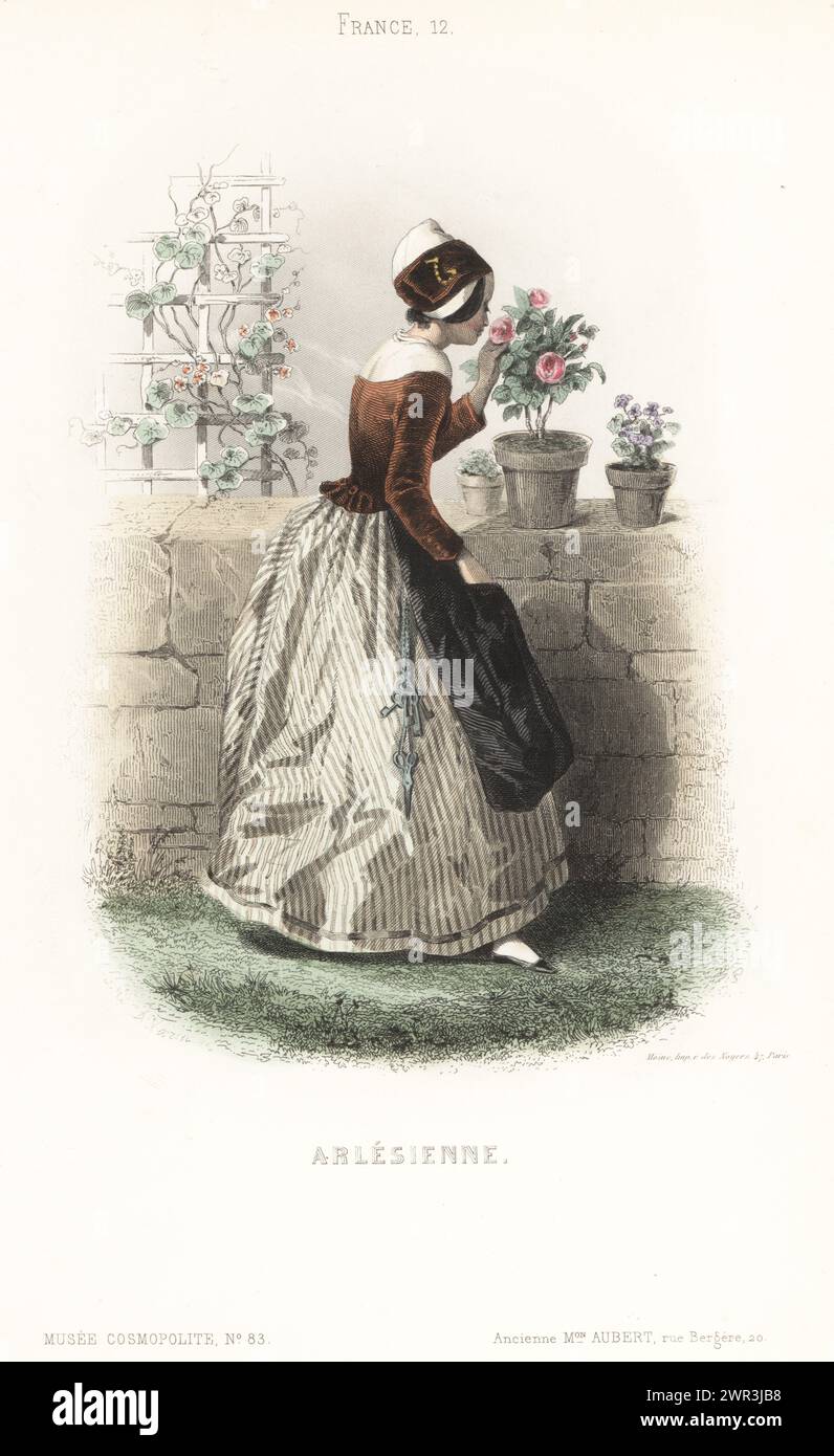 Costume of a woman of Arles, Provence, France. In Ruban headdress, with a wide ribbon pinned onto a folded cap, brown bodice, striped skirts, black apron, keys and scissors hanging on a chain from her waist. She is smelling a rose in a flowerpot in a garden. Arlesienne. Handcoloured steel engraving after an illustration by Adolphe or Amédée Varin from Musée Cosmopolite, Musée de Costumes, Cosmopolitan Museum, published by ancienne maison Aubert, Paris, 1850. Stock Photo
