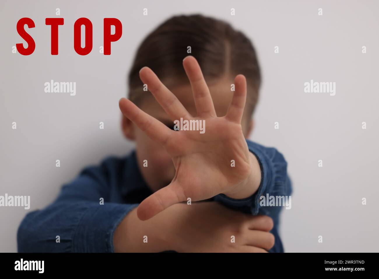 No child abuse. Girl making stop gesture near white wall, selective focus Stock Photo