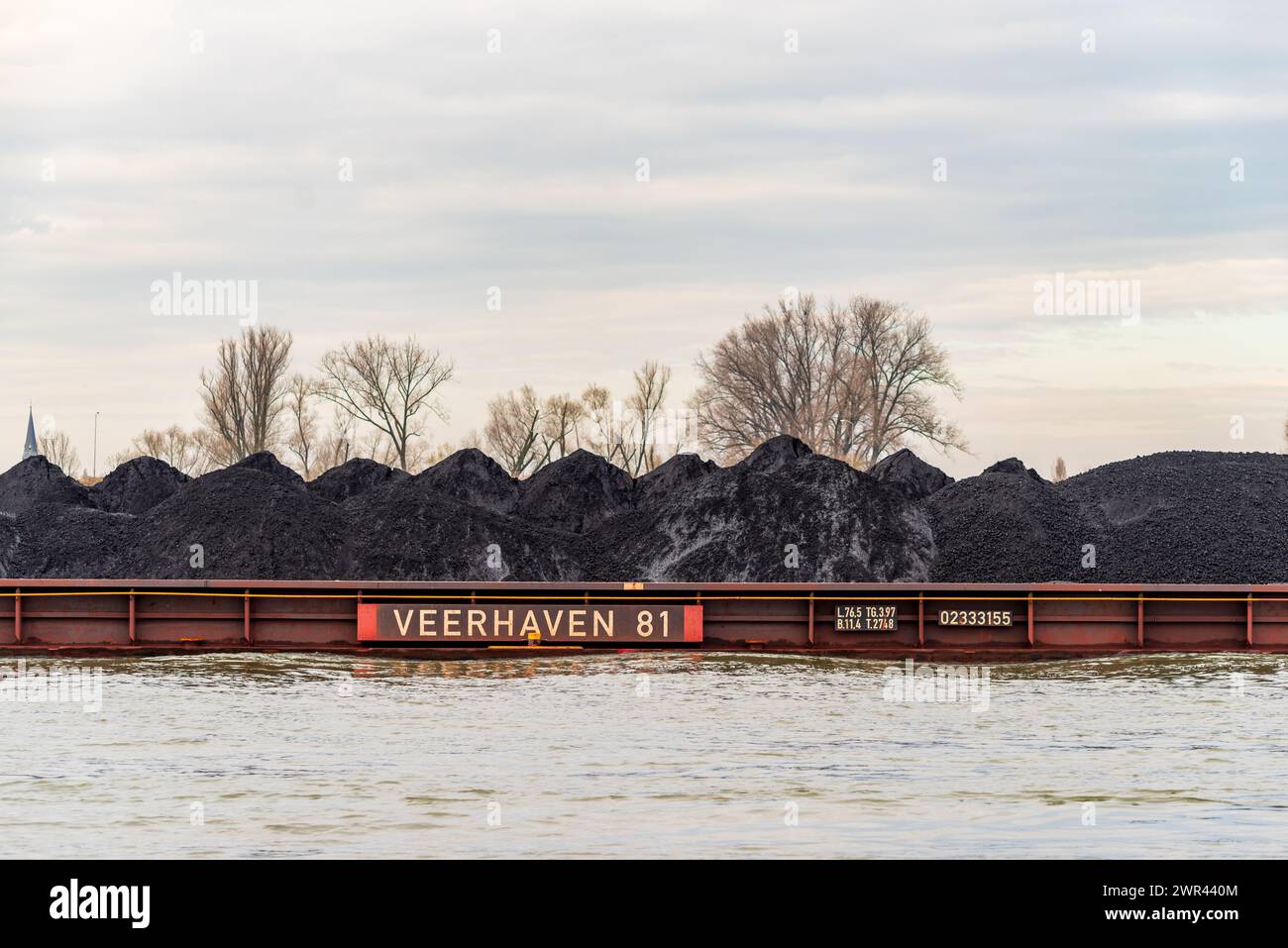 NIJMEGEN, NETHERLANDS - MARCH 9, 2024: Enormous dutch barge navigating the Waal river with a load of black sand Stock Photo
