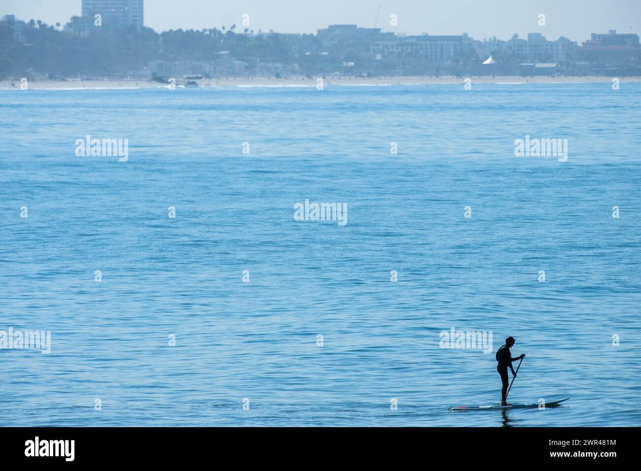 Stand-up Paddle Board surfers surfing at sunset Beach in Pacific Palisades, California, USA. Stock Photo