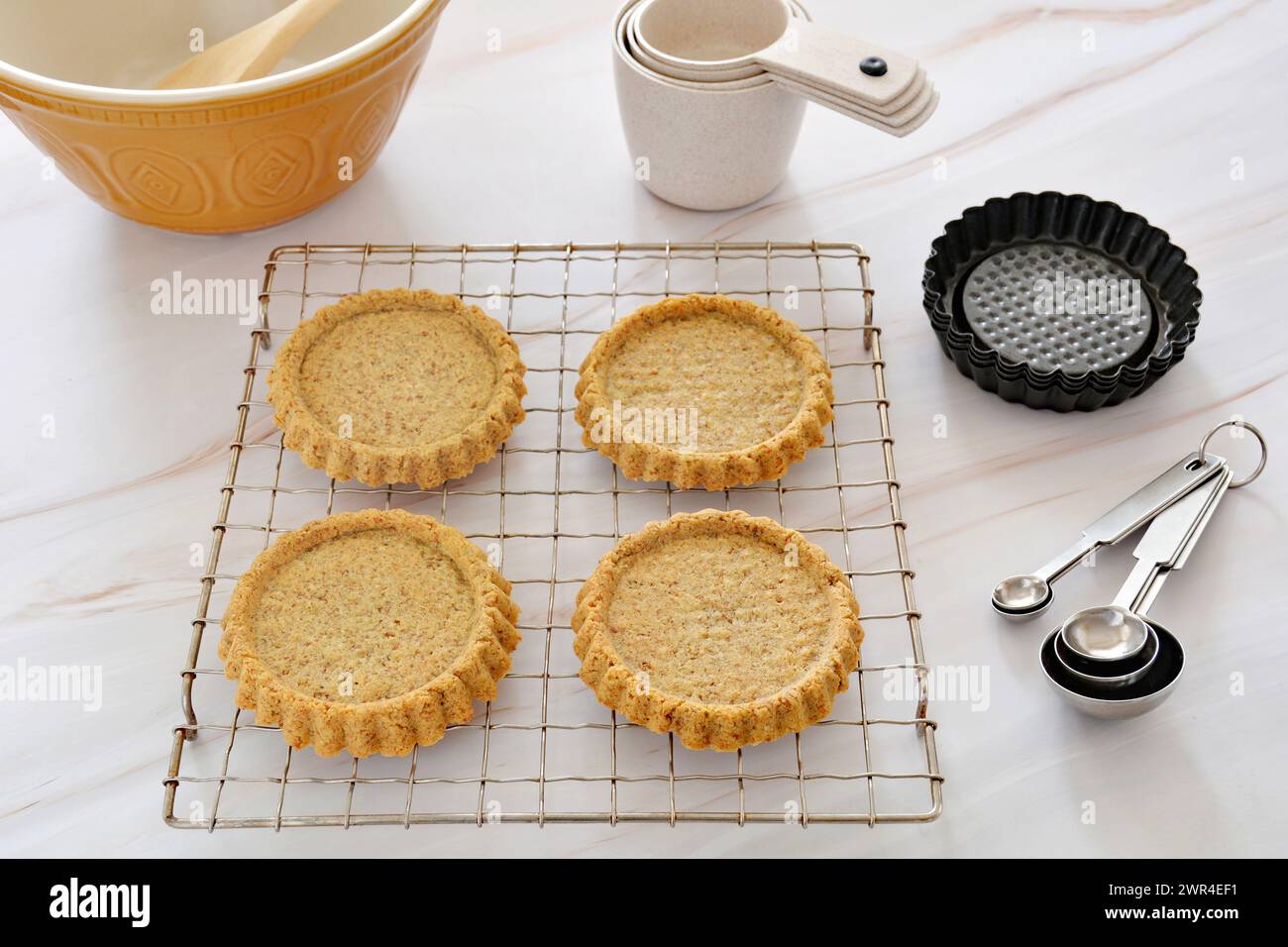 Healthy almond and flax meal cakes baked on fluted tart shells with baking utensils in