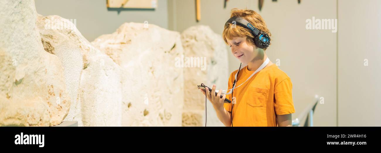 Boy looking at sculptures and listening to audio guide at museum ...