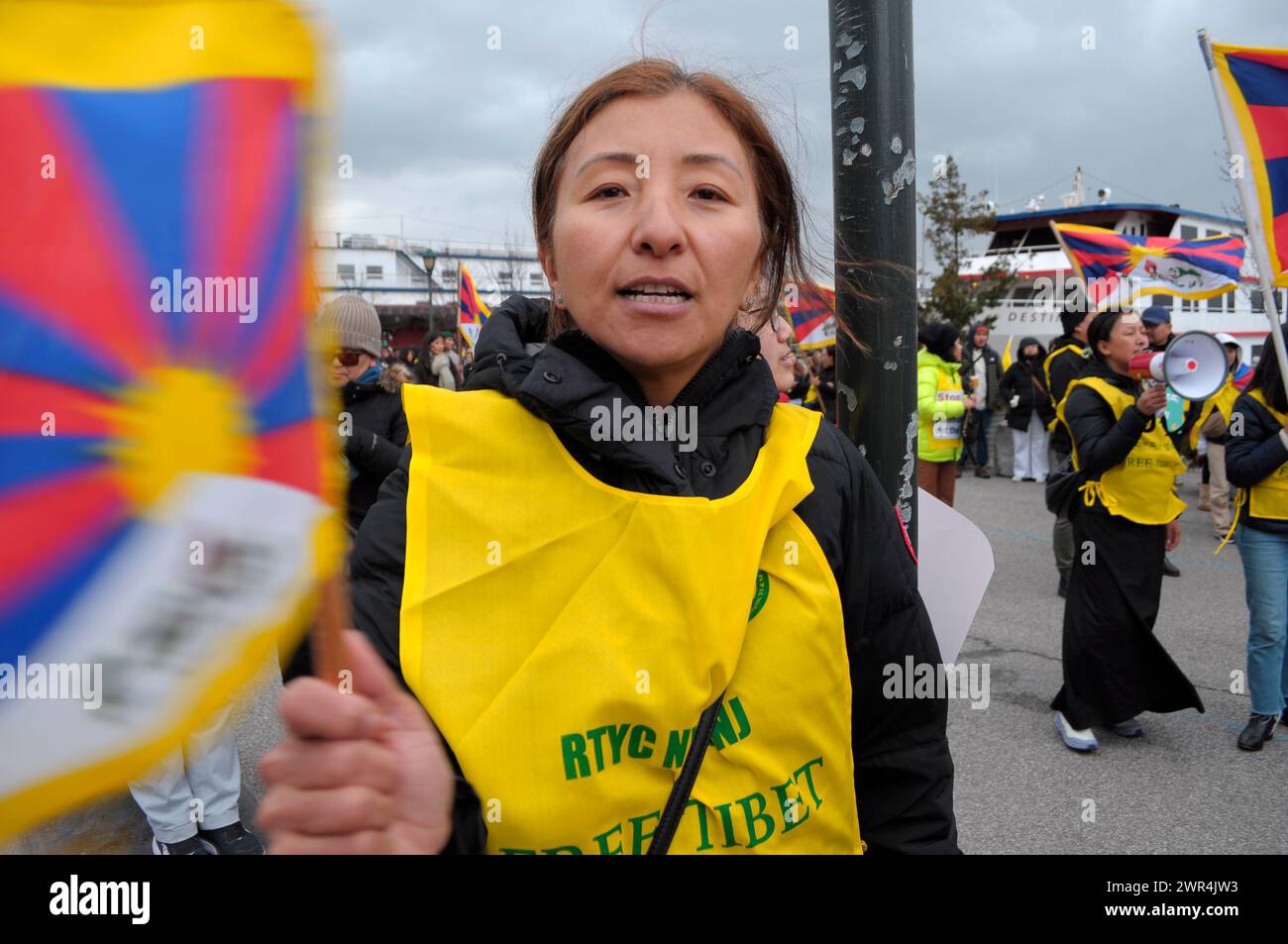 A pro-Tibet demonstrator waves the Tibetan flag at a rally near the building of the Consulate General of the People's Republic of China in New York during the 65th Tibetan Uprising Day. Demonstrators rallied in Manhattan, New York City demanding Tibet's independence from China. The Tibetan Uprising Day marks the day in 1959 when thousands of Tibetans in Tibet surrounded the palace of the current and 14th Dalai Lama. The Dalai Lama is the spiritual Buddhist leader of Tibetans worldwide. The Tibetans surrounded the palace in 1959 to protect the Dalai Lama due to fears of a Chinese government plo Stock Photo