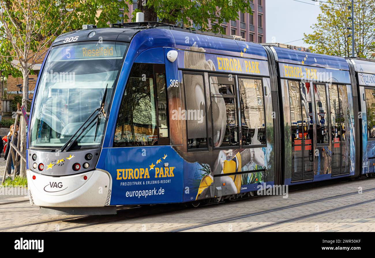 Eine Strassebahn der Linie 5 mit Ziel Risefeld fährt beim Platz der alten Synagoge vorbei. Das Tram hat seitlich Werbung des Europa Park in Rust. (Fre Stock Photo