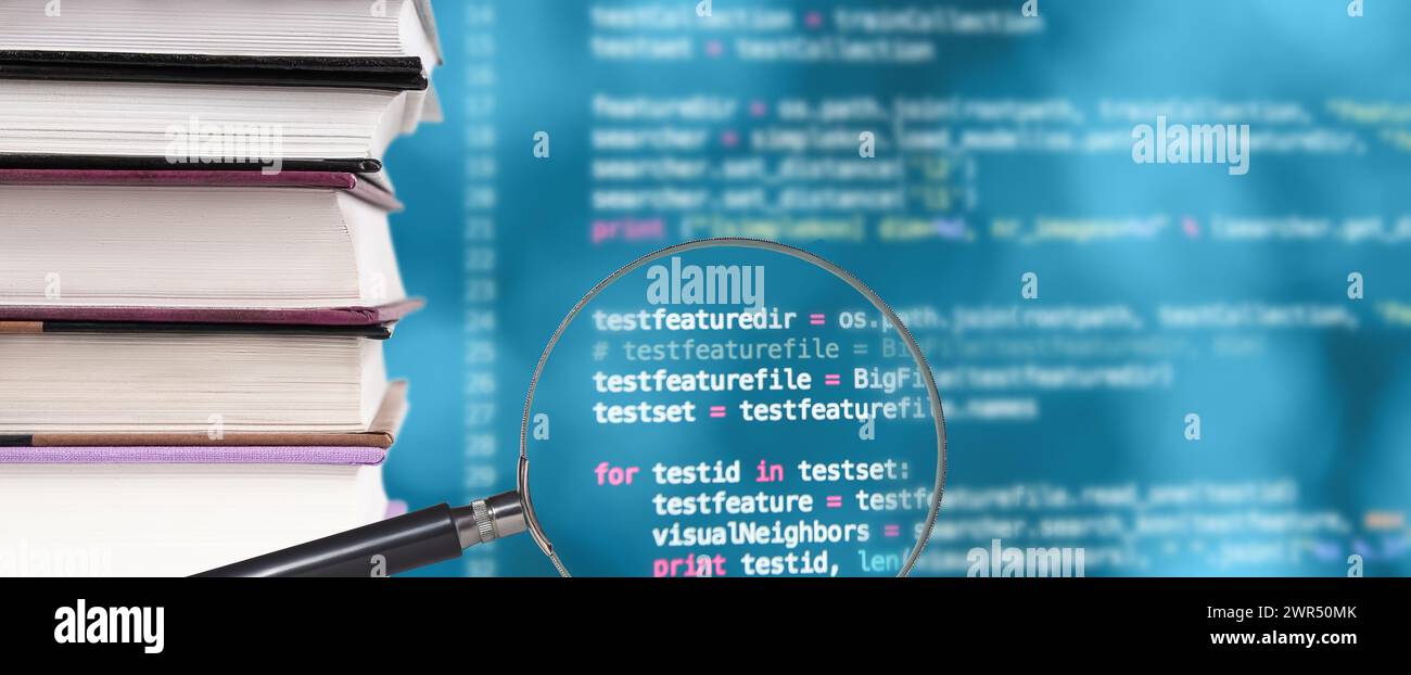 Stack of books, source code and magnifying glass on a blurred background Stock Photo