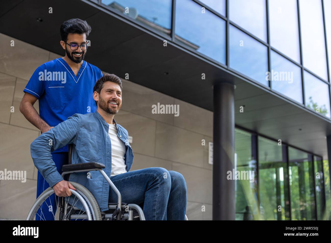 Male nurse in a blue doctors overall with a wheelchair Stock Photo