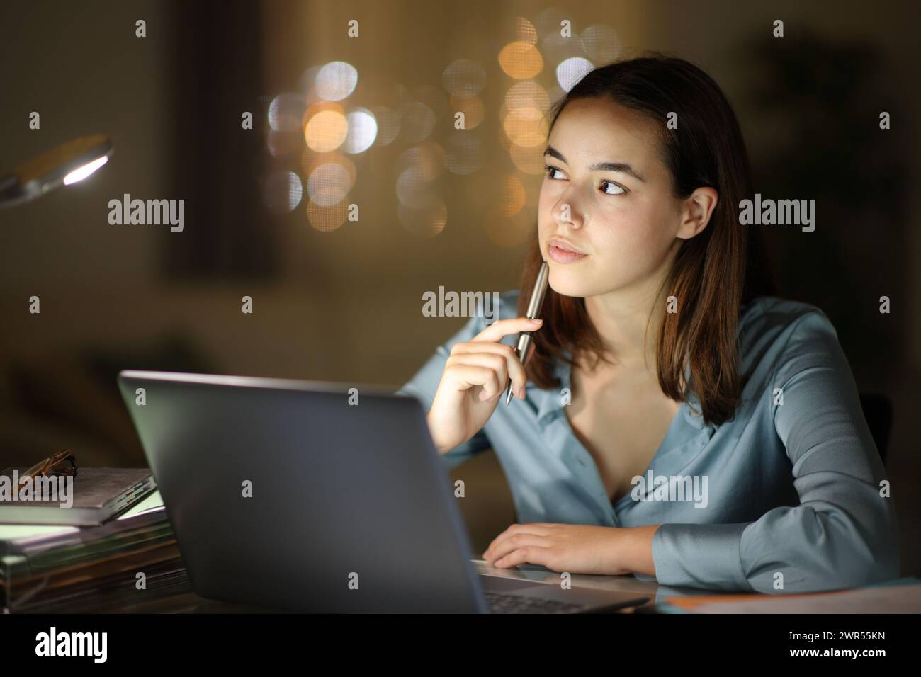Serious tele worker in the night thinking looking at side and working at home Stock Photo