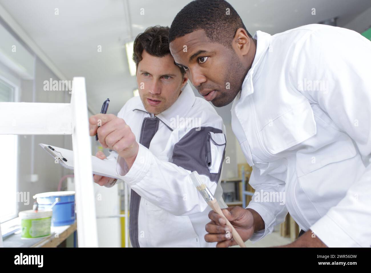 foreman advising male painter apprentice Stock Photo