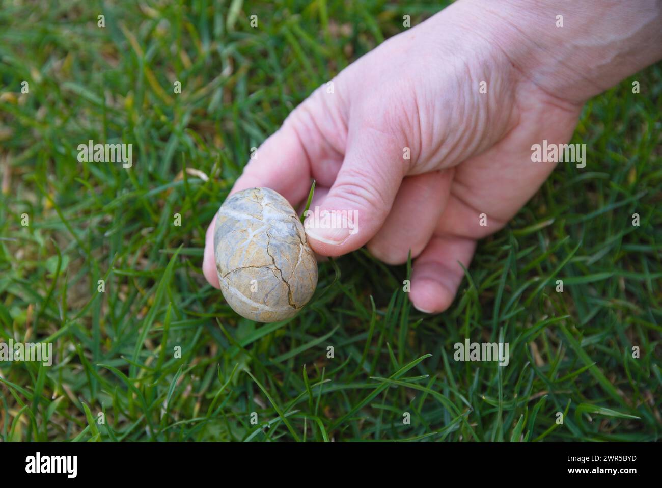 Easter Egg Made Of Stone With Cracks And Fissures In The Hand Stock Photo