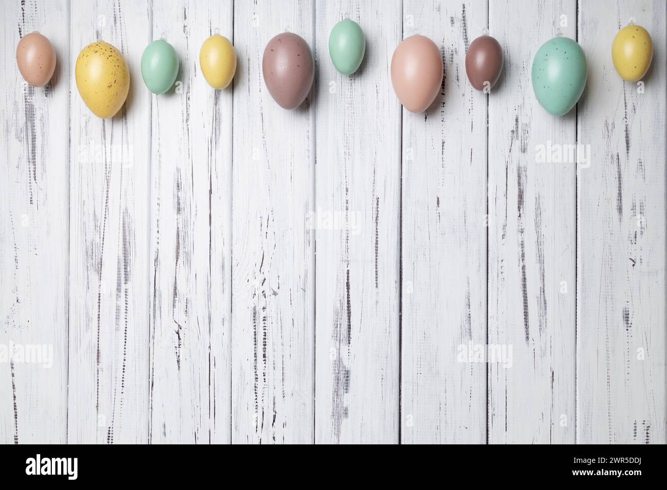 Multicoloured Easter eggs on white vintage aged wooden background. Copy space Stock Photo
