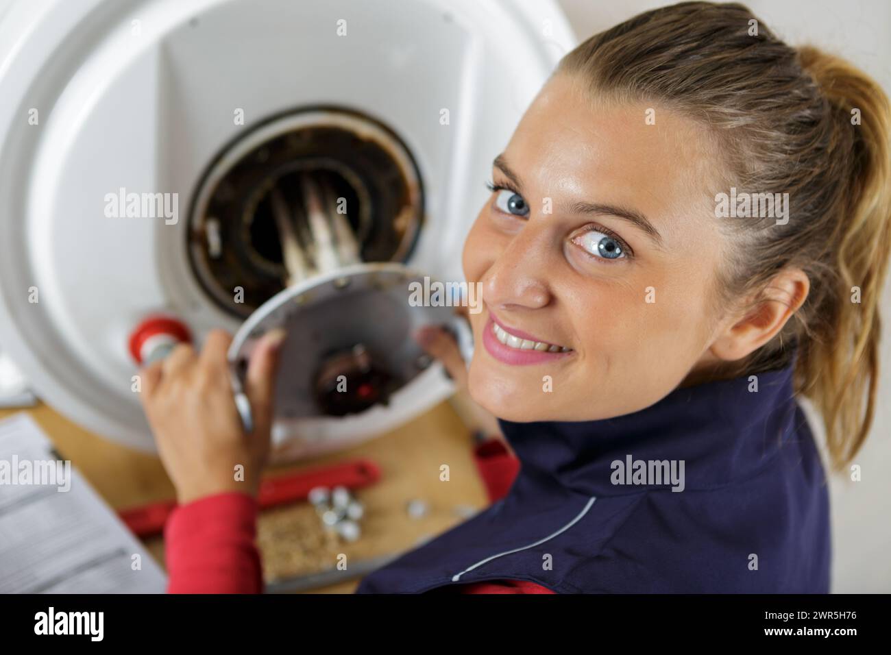female trainee plumber working on central heating boiler Stock Photo
