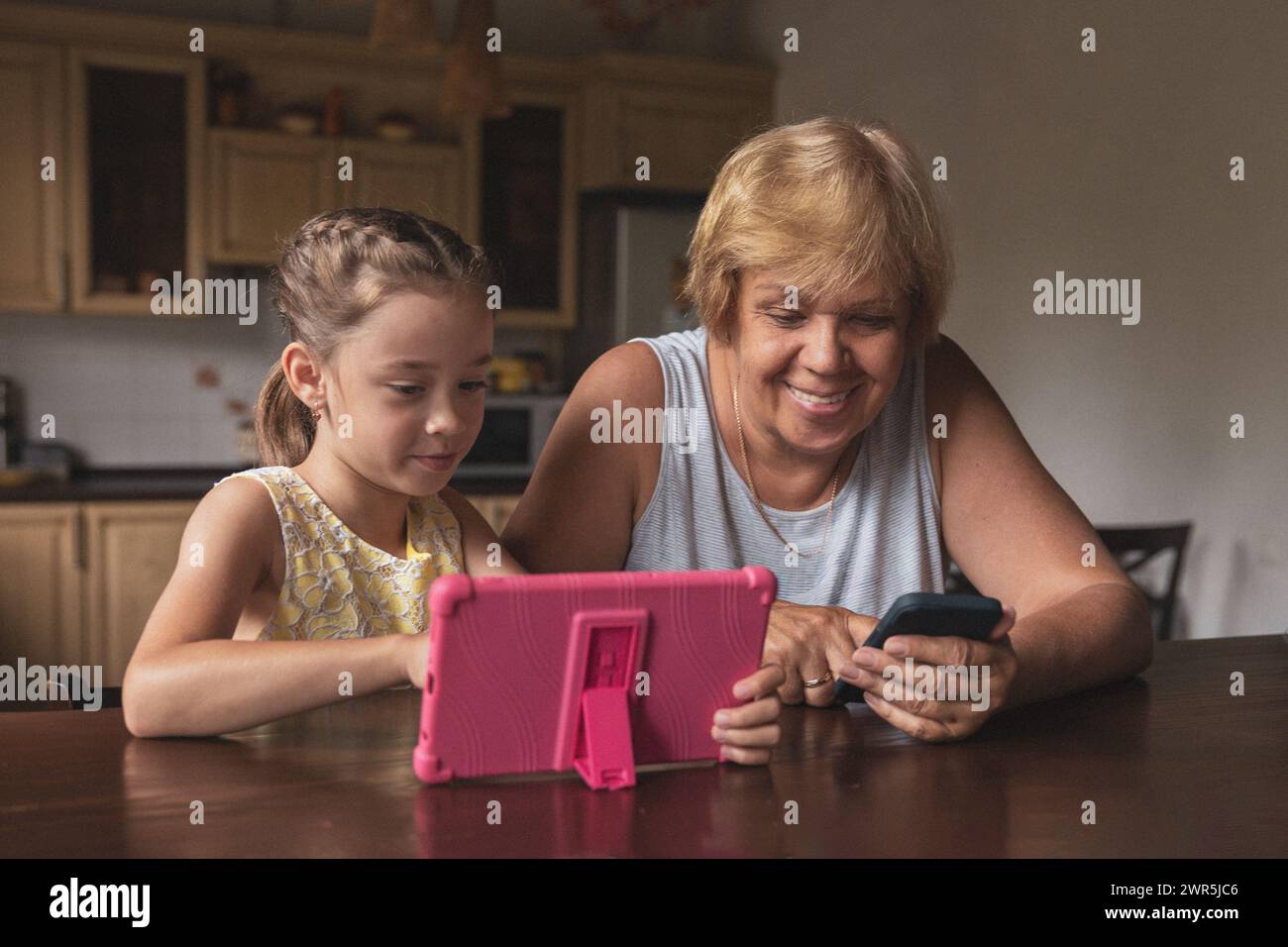Girl and grandma looking at gadgets in the kitchen Stock Photo