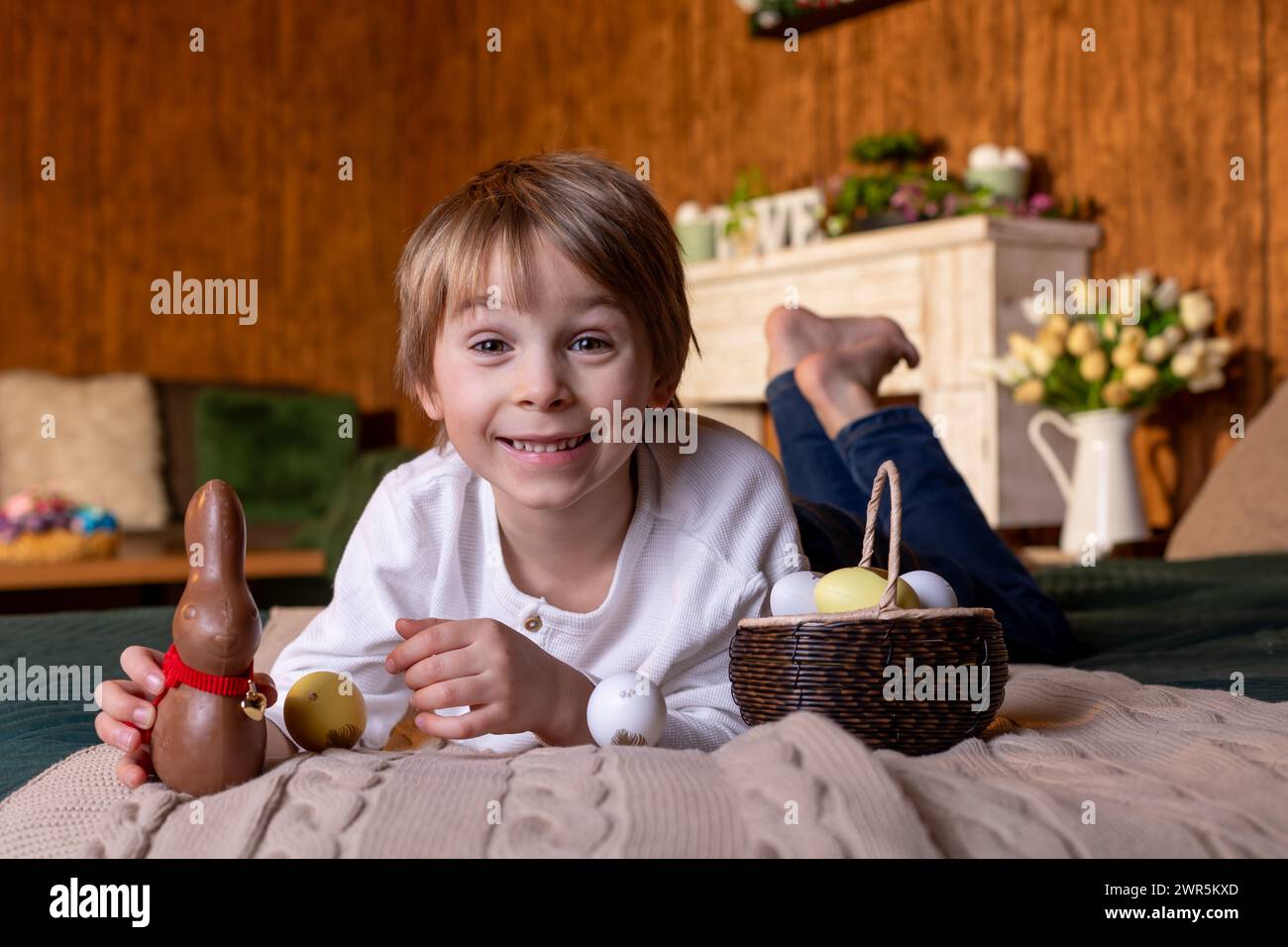 Cute school child, boy, holding basket with easter eggs on easter background, studio shot Stock Photo