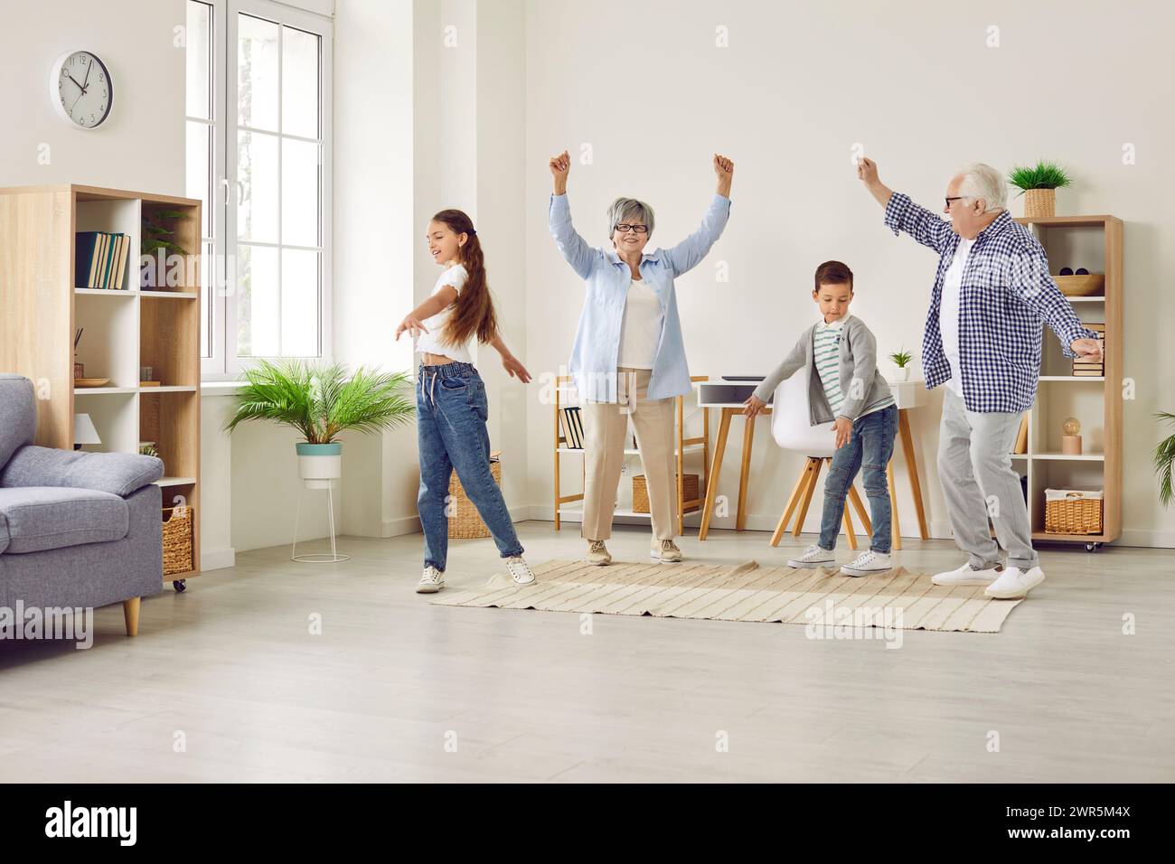 Happy grandparents and children playing, dancing and having fun together at home Stock Photo